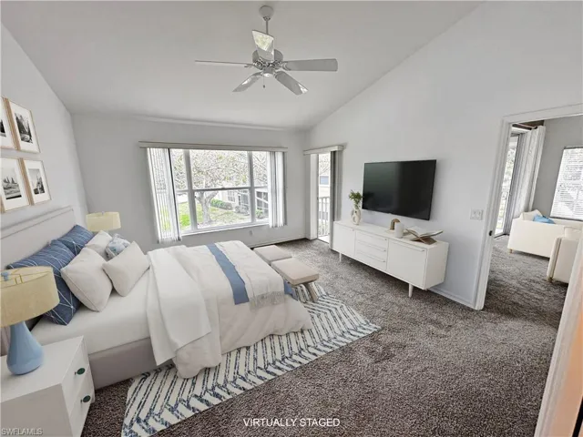 Bedroom with dark carpet, ceiling fan, and lofted ceiling
