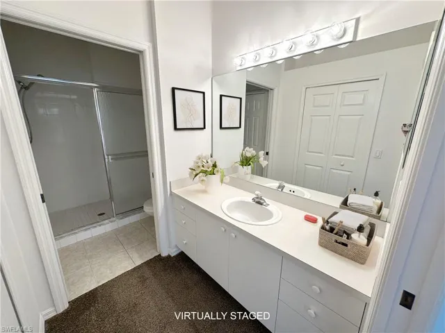 Bathroom with tile patterned floors, vanity, a shower with shower door, and toilet