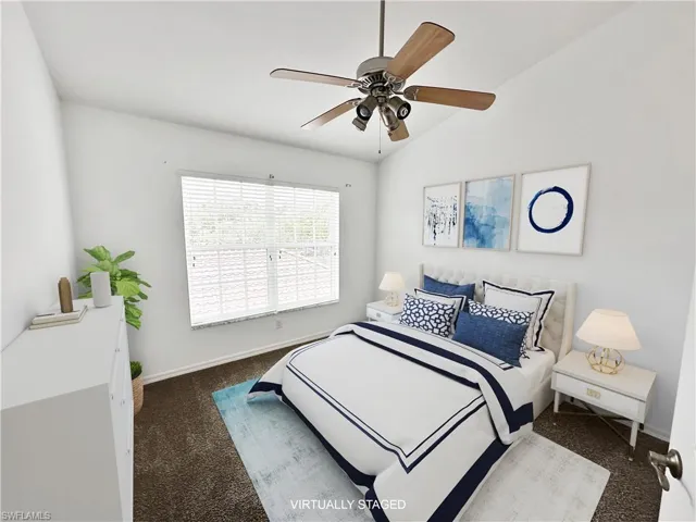 Bedroom with dark carpet, vaulted ceiling, and ceiling fan