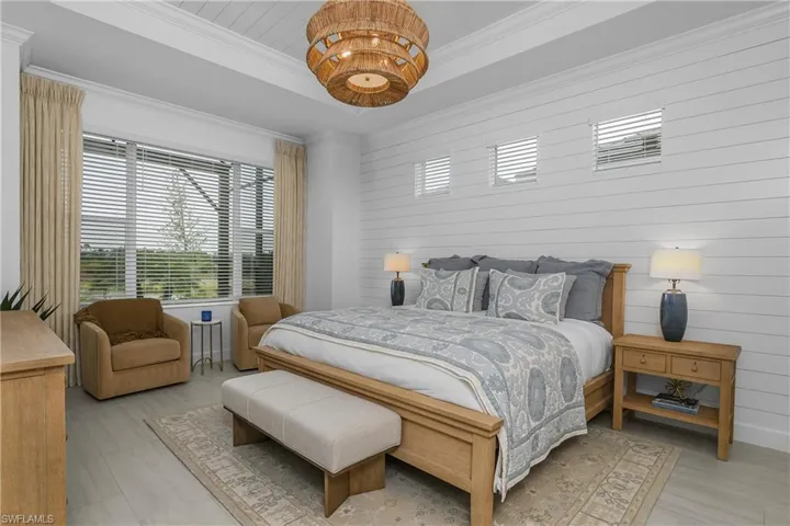 Bedroom with wooden walls, a tray ceiling, and crown molding
