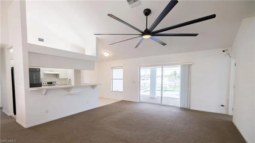 View from front entrance: living room with ceiling fan, and high vaulted ceiling