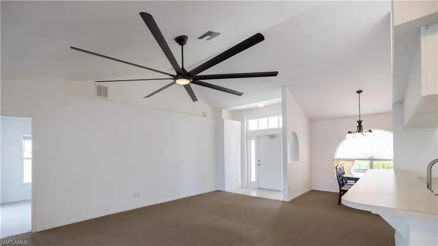 View from sliding doors: living room with a ceiling fan, high vaulted ceiling, and a chandelier