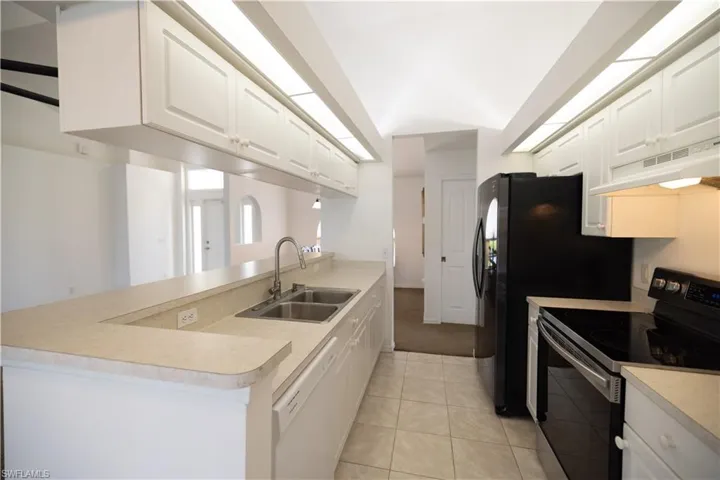 Kitchen featuring stainless steel range with electric cooktop, dishwasher, a peninsula, under cabinet range hood, and white cabinets