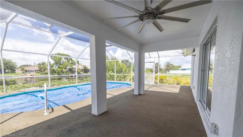 View of swimming pool with a water view, a ceiling fan, and a screened patio area