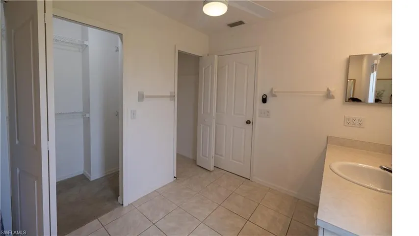 Bathroom featuring vanity, a ceiling fan, and a walk in closet