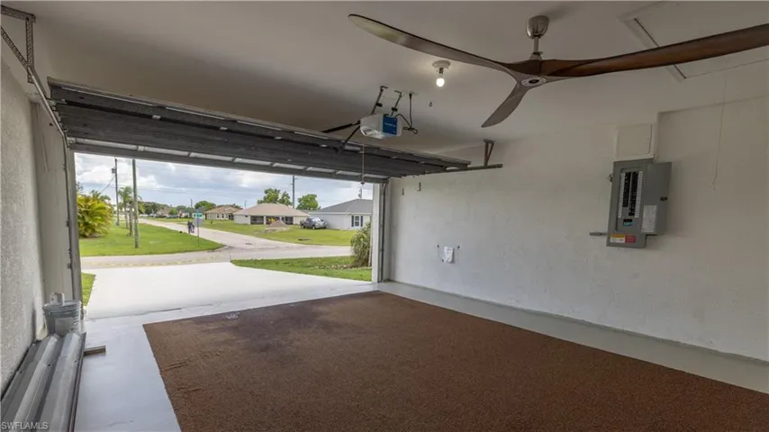 Two car Garage featuring electric panel, shutters, garage door opener, and ceiling fan