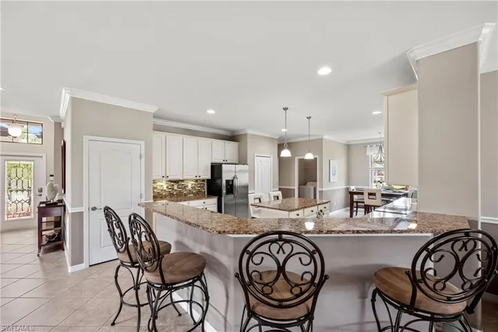 Kitchen with under cabinet lighting, stainless steel appliances, light tile floors and a breakfast bar area