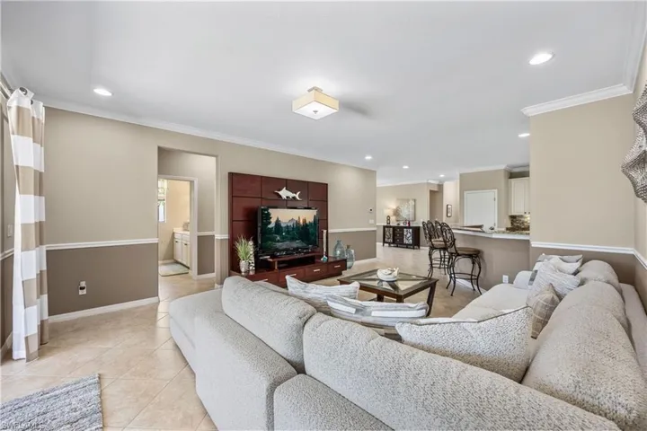 Bright neutral great room featuring light tile floors and crown moldings
