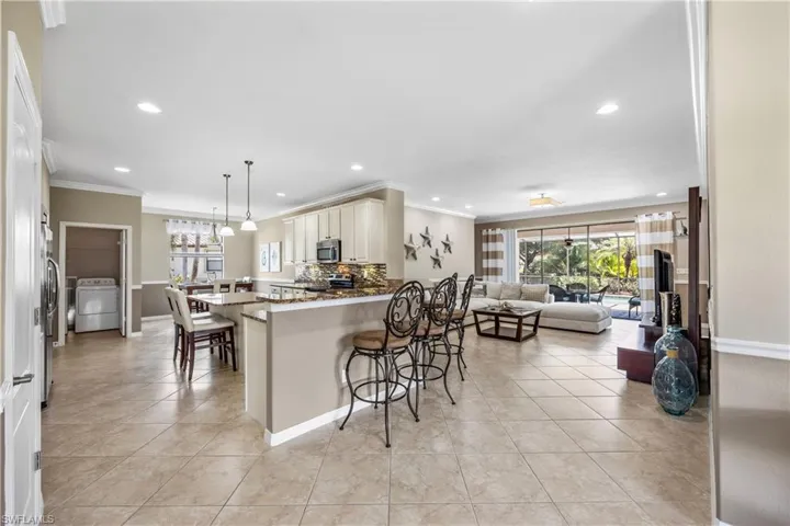 Kitchen featuring stainless steel appliances, kitchen peninsula, stone countertops, washer / dryer, and a breakfast bar