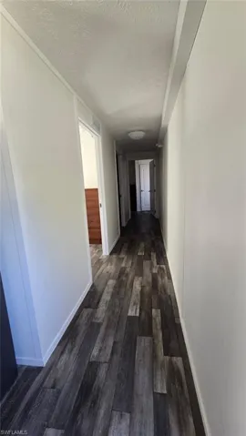 Hall featuring dark wood finished floors and a textured ceiling
