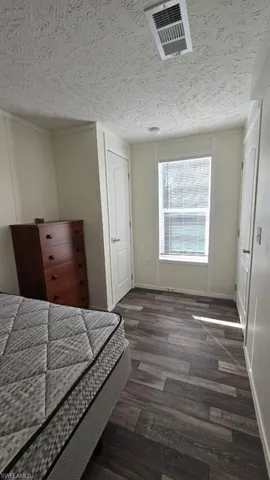 Bedroom featuring dark wood-style flooring and a textured ceiling