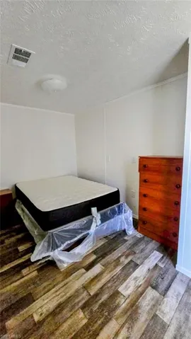 Bedroom with wood finished floors and a textured ceiling