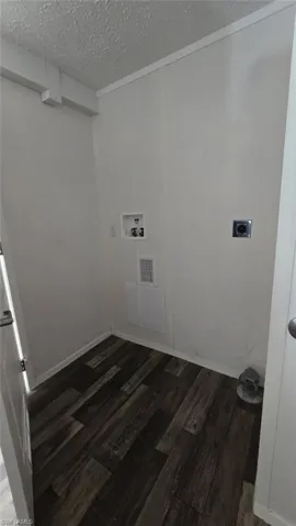 Laundry room featuring dark wood-style floors, a textured ceiling, hookup for a washing machine, and hookup for an electric dryer