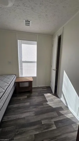 Bedroom featuring a textured ceiling and dark wood-style floors