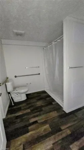 Bathroom with dark wood finished floors and curtained shower