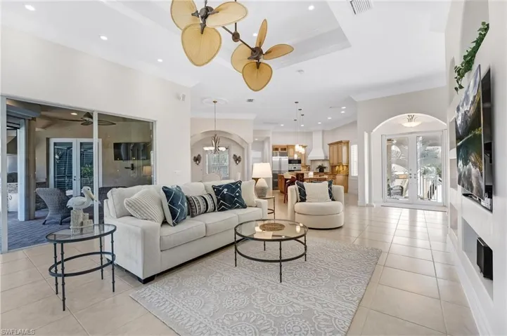 The main living area is elegantly finished with beautiful porcelain tile flooring and enhanced by soaring tray ceilings that create a grand sense of volume and sophistication. Architectural archways lend a refined, modern aesthetic, while custom built-ins add both style and functional elegance, completing this impeccably designed space.
