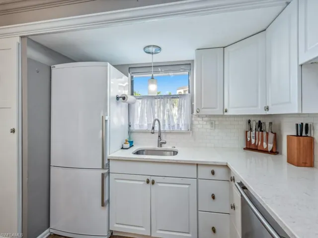 Kitchen with white refrigerator, decorative light fixtures, and white Custom cabinetry