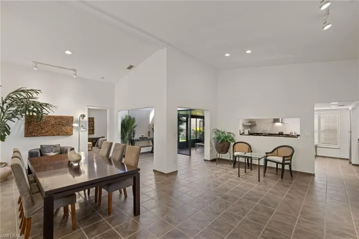 Dining area with track lighting, tile patterned floors, and a high ceiling