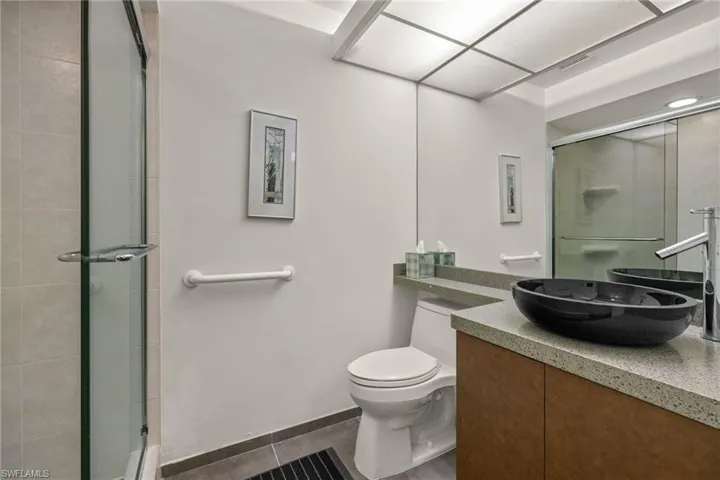 Bathroom with vanity, a shower with shower door, tile patterned floors, and toilet