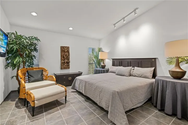 Tiled bedroom with lofted ceiling and rail lighting