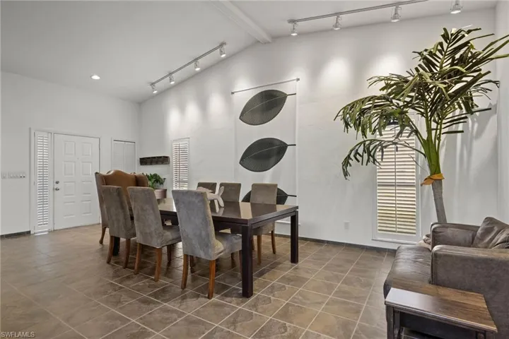 Dining space with track lighting, beam ceiling, and high vaulted ceiling