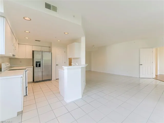Kitchen featuring white appliances, white cabinetry, light countertops, light tile patterned floors, and recessed lighting