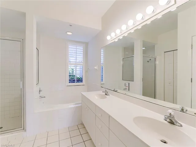 Bathroom featuring a closet, light tile patterned flooring, a garden tub, and a shower stall
