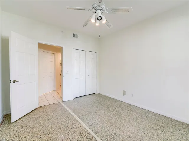 Unfurnished bedroom with a closet, ceiling fan, and speckle patterned floor