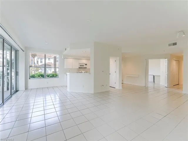 Unfurnished living room featuring light tile patterned floors and baseboards