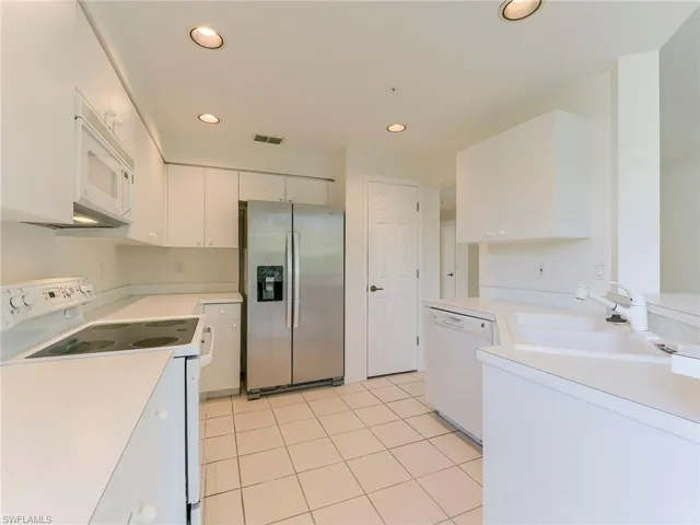 Kitchen with white appliances, light countertops, recessed lighting, white cabinets, and light tile patterned flooring