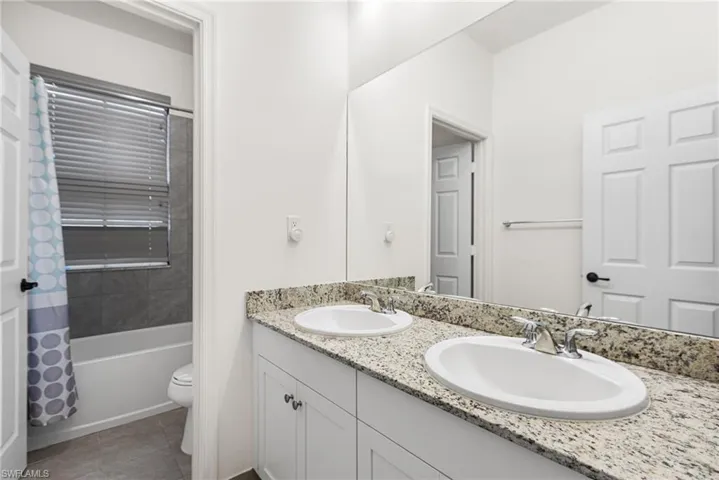 Full bathroom featuring tile patterned flooring, vanity, shower / bath combination with curtain, and toilet