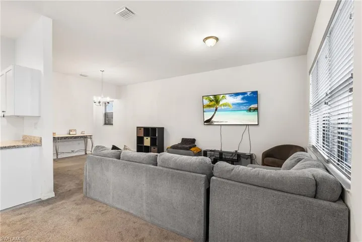 Living room with light colored carpet and a chandelier