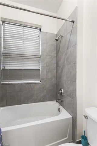 Bathroom with toilet and tiled shower / bath combo