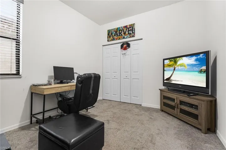 Home office featuring vaulted ceiling and light colored carpet