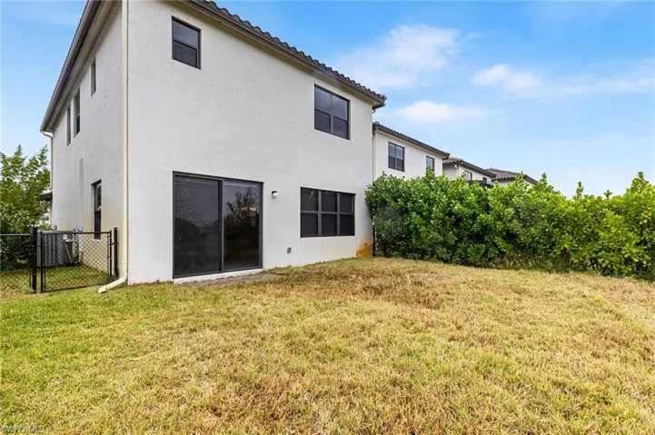 Back of property featuring cooling unit and a lawn