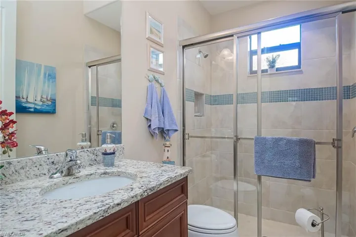 Bathroom featuring vanity, toilet, and an enclosed shower