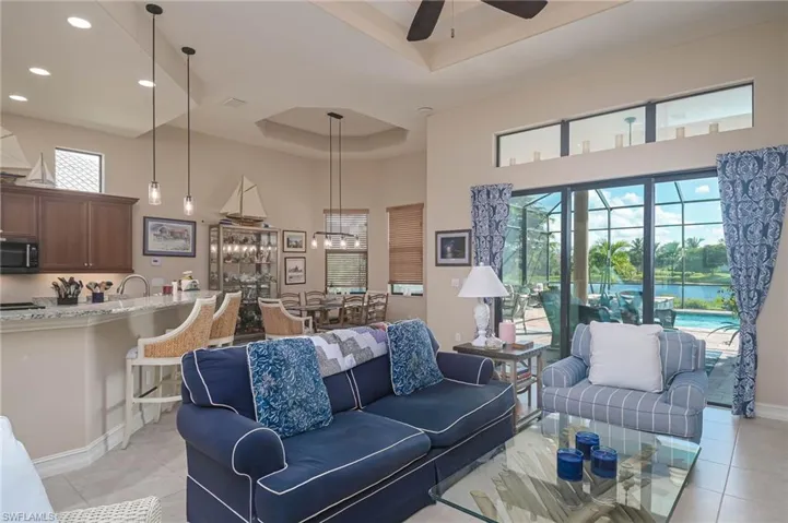 Living room featuring a towering ceiling, ceiling fan, plenty of natural light, and light tile patterned floors