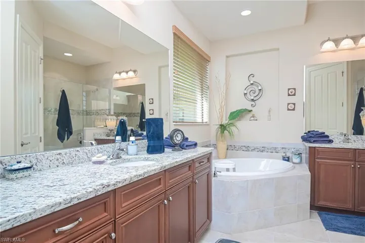 Bathroom featuring shower with separate bathtub, tile patterned flooring, and vanity