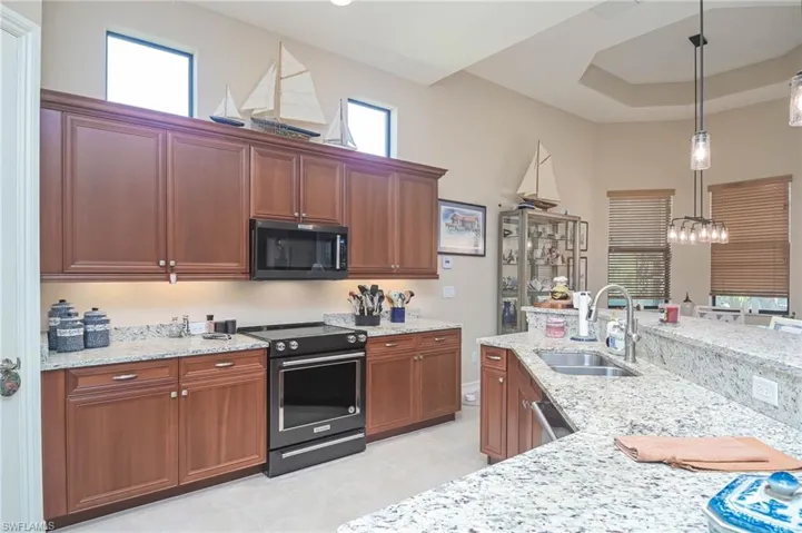 Kitchen featuring sink, decorative light fixtures, plenty of natural light, and range with electric stovetop