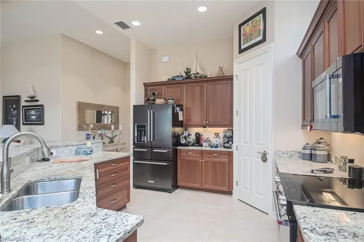 Kitchen with light stone counters, black range, sink, and high end fridge