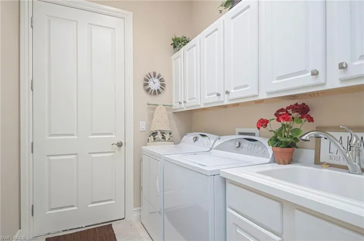Clothes washing area featuring cabinets, sink, and washing machine and dryer