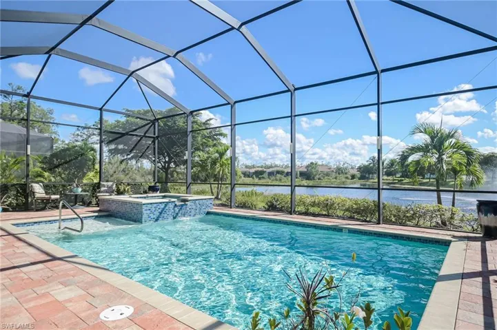View of swimming pool featuring a lanai, a patio, a water view, and an in ground hot tub