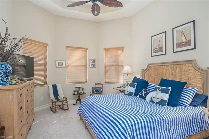 Bedroom with multiple windows, ceiling fan, and light carpet