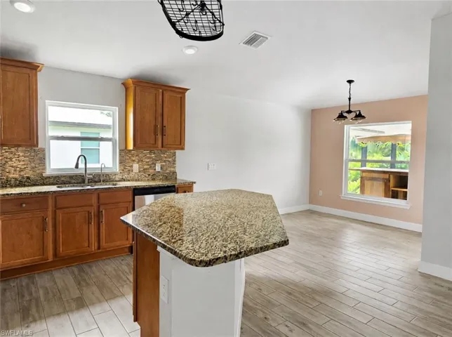 Kitchen featuring wood-finish cabinetry, granite countertops, a mosaic tile backsplash, and stainless steel appliances