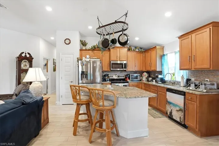 Kitchen featuring a kitchen bar, open floor plan, stainless steel appliances, light wood-type flooring, and a kitchen island