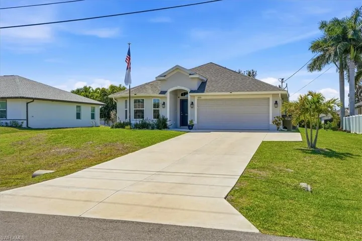 Ranch-style home featuring an attached garage, a front lawn, concrete driveway, stucco siding, and roof with shingles
