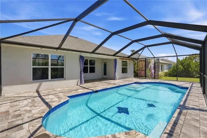 Screened lanai with a rectangular pool, paver deck, and stucco exterior