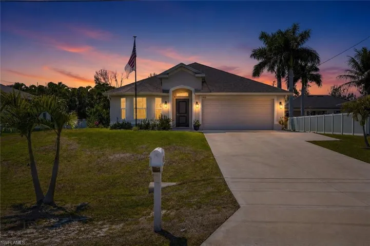 Single-story residence featuring a two-car garage, concrete driveway, and a white fence