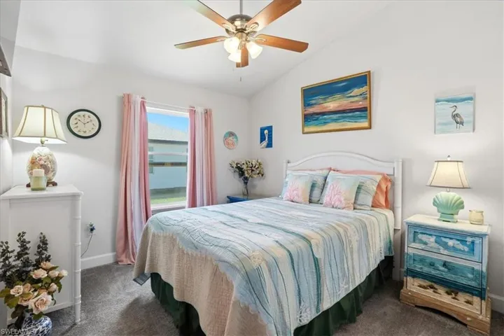 Bedroom with lofted ceiling, dark colored carpet, and a ceiling fan