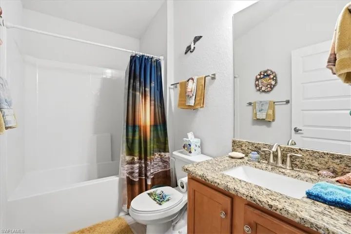 Full bathroom with vanity, shower / bath combo with shower curtain, and a textured wall